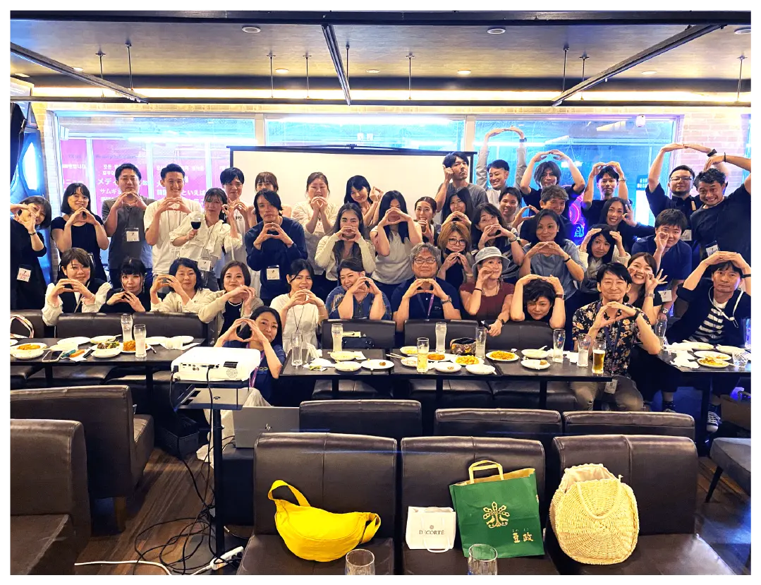 A large group forms heart shapes with their hands at a lively party.