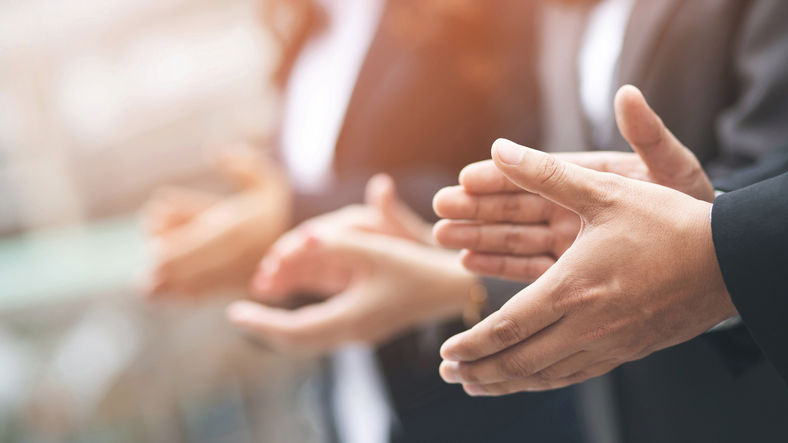 Business professionals applauding during a corporate event.