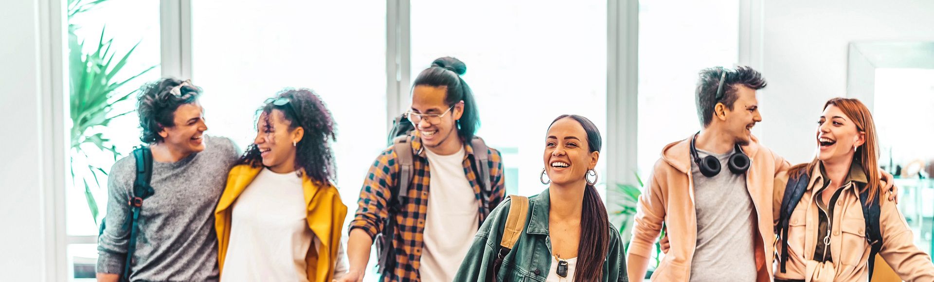 Diverse group of young adults walking together indoors, smiling and talking.
