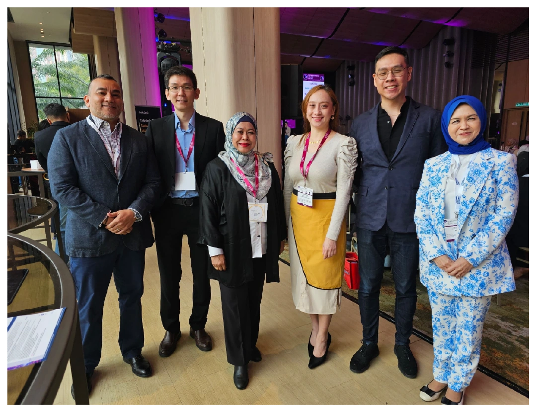 A diverse group of professionals poses together at an indoor conference event.