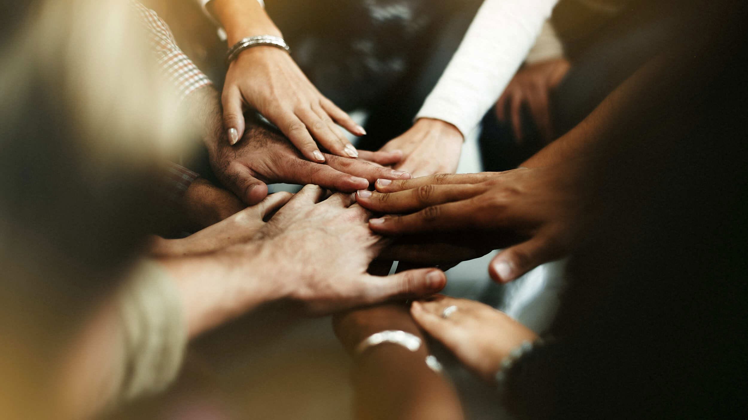 Group of diverse hands stacked together in a teamwork gesture.