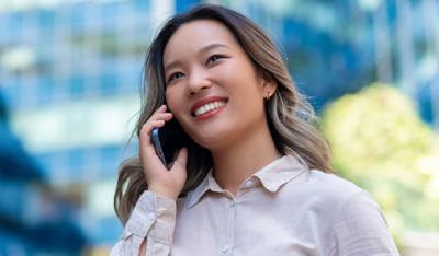 Smiling Asian business woman talking on the phone in the streets