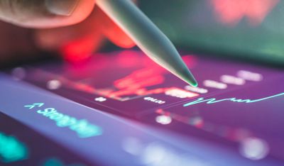 Hand holding a pencil while clicking on a computer screen.