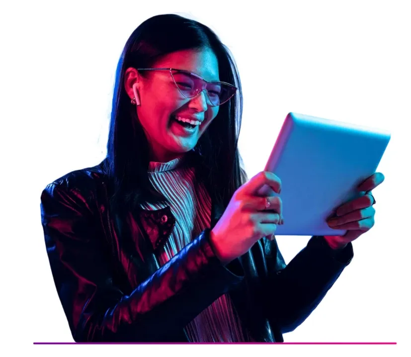 Smiling woman wearing glasses and headphones holding a tablet with colorful neon lighting.