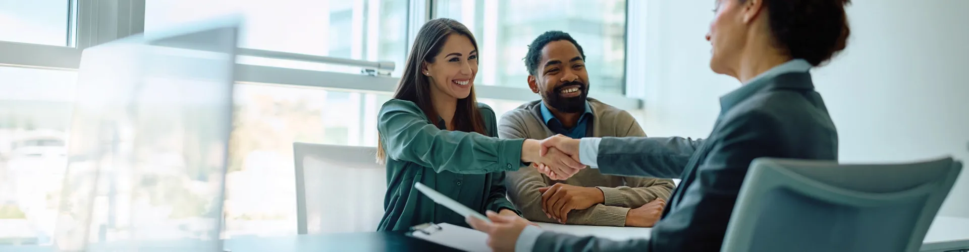 Couple greeting a financial services professional in a business setting.
