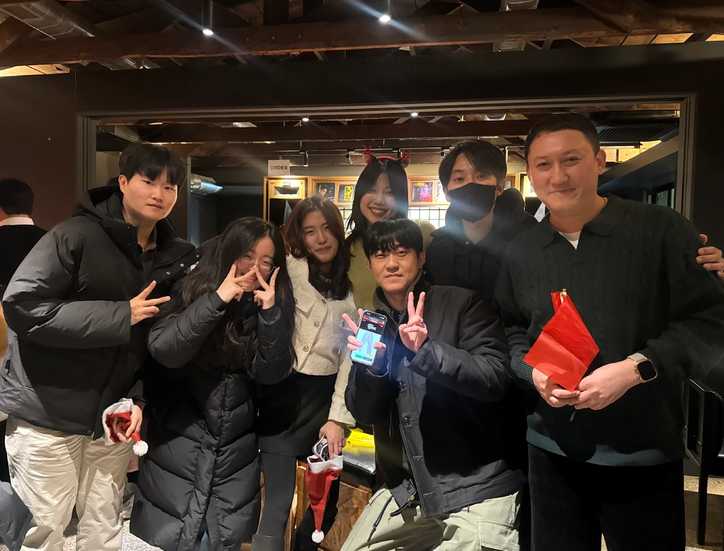 A small group of colleagues pose cheerfully together at a festive indoor gathering.