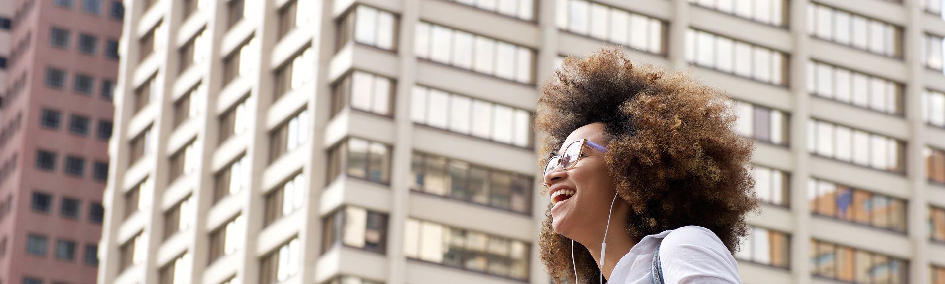 Young woman laughing while walking with headphones, blog on TP’s year-round support for women and families in Tunisia.