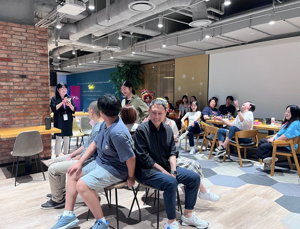 Colleagues relax and laugh together during a casual indoor office gathering.