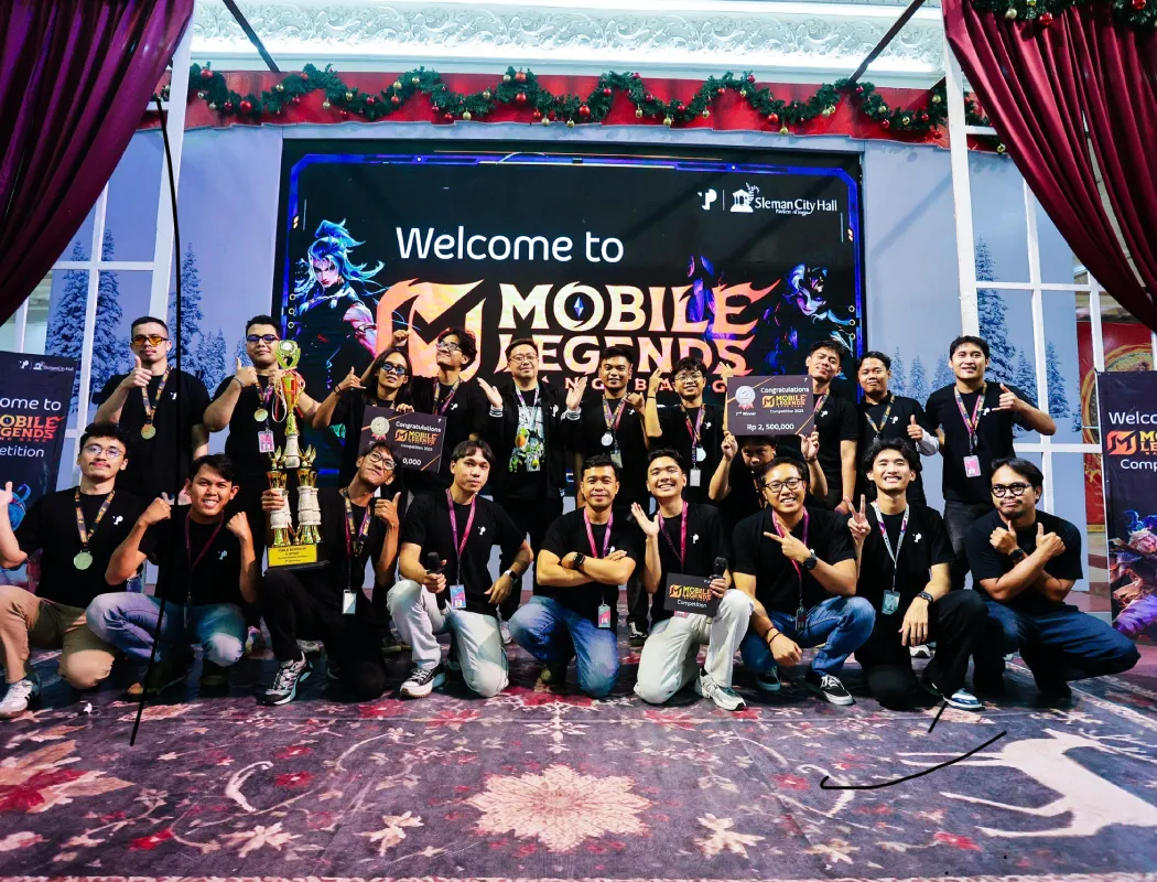 A team celebrates at a Mobile Legends competition event, posing with trophies and prizes on stage.