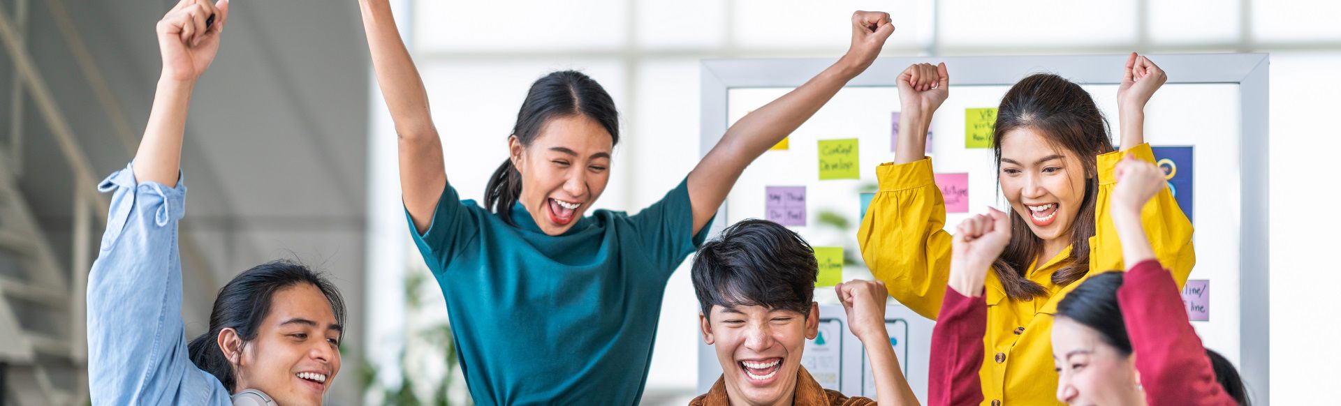 Celebrating team success with raised arms during a collaborative work session.