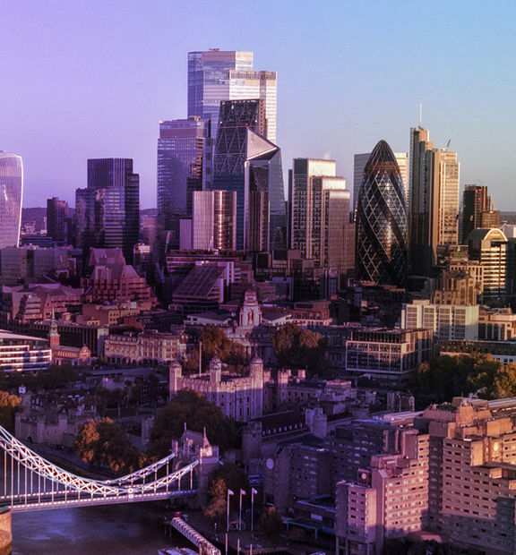 Aerial view of the City of London skyline at sunset, with the River Thames and modern skyscrapers. 