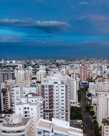 Cluster of high-rise buildings under a bright blue sky with scattered clouds, forming a modern cityscape