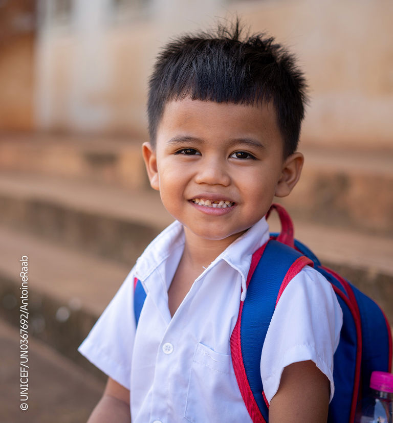 Smiling young boy preparing for school with his backpack.