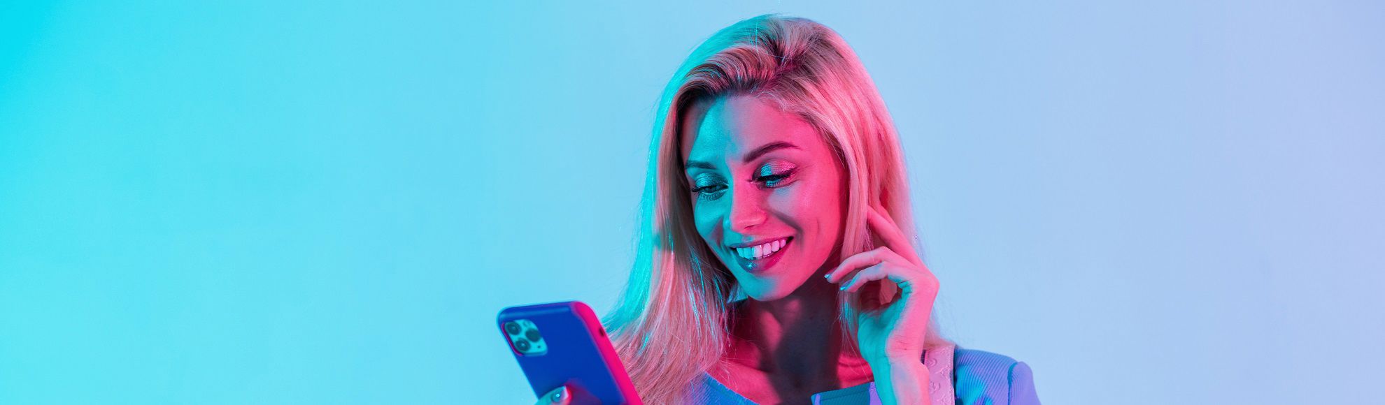 Smiling woman looking at her smartphone against a colorful gradient background.