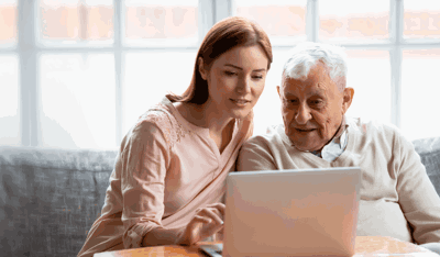 Woman teaching man how to use computer
