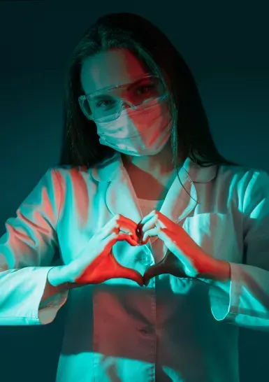 Masked healthcare worker making a heart gesture.