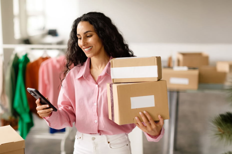 Woman holding delivery boxes and her cellphone