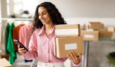 Woman holding delivery boxes and her cellphone