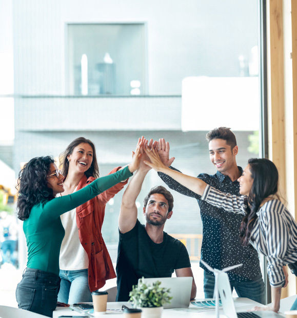 Equipo de colegas celebrando un logro con un choque de manos en una oficina.