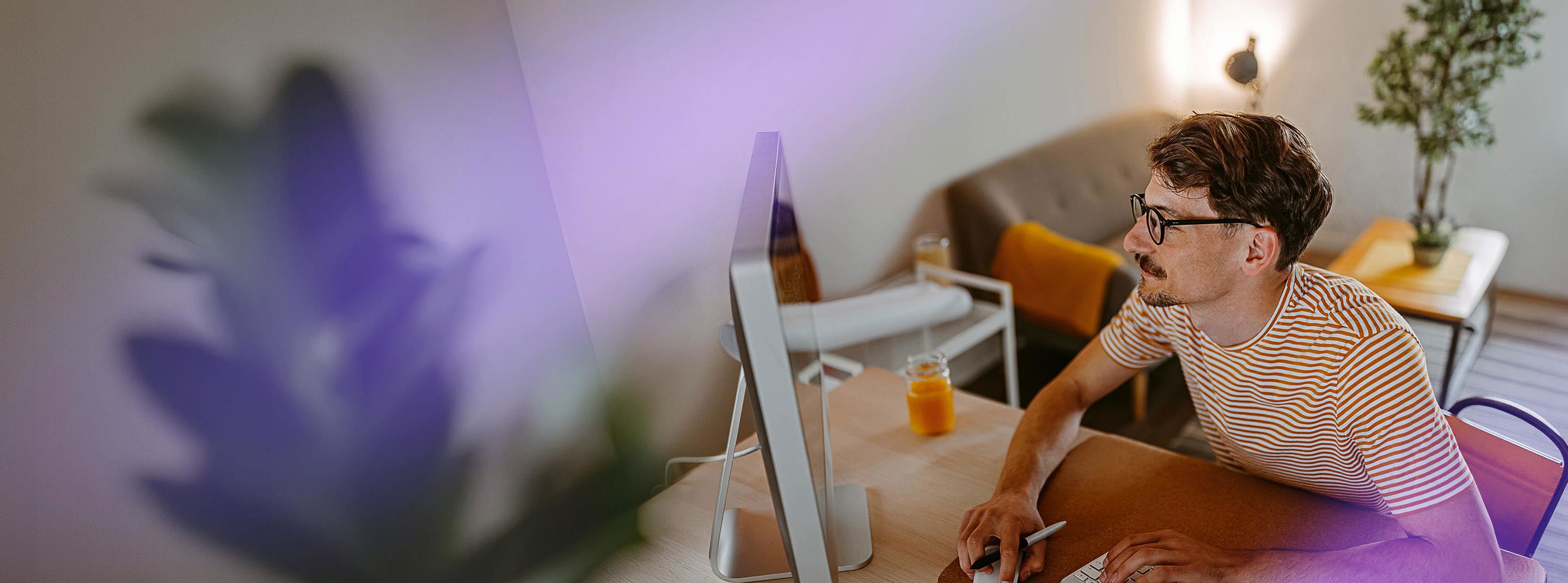 Man working at a desktop computer in a home office for TP.