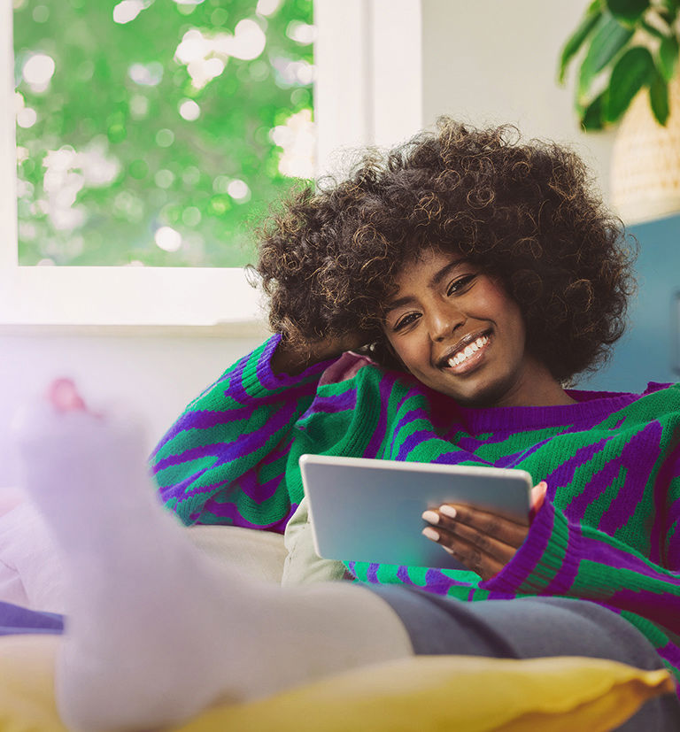 Afro descendant woman with a leg cast using a tablet, reflecting trusted digital healthcare support.