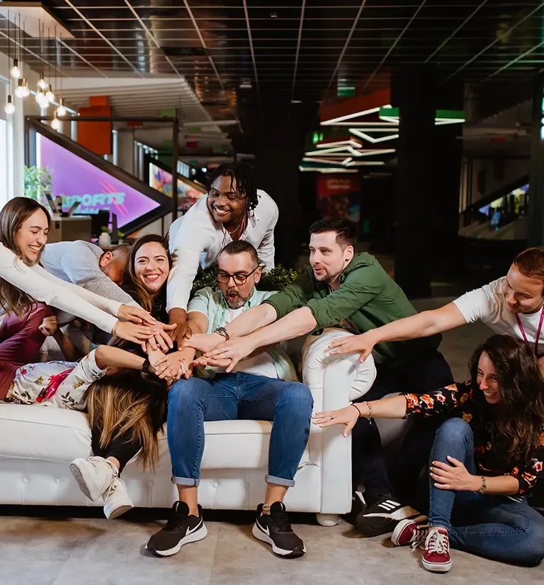Colleagues joining hands and smiling together in a collaborative workplace.