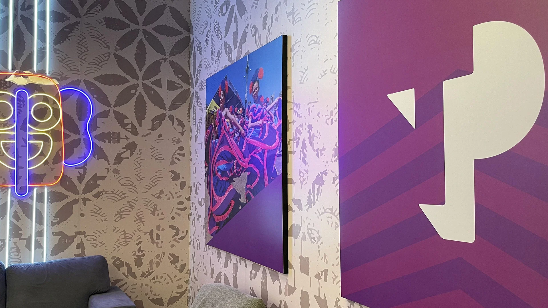 TP office wall with neon butterfly sign and colorful artwork celebrating culture.