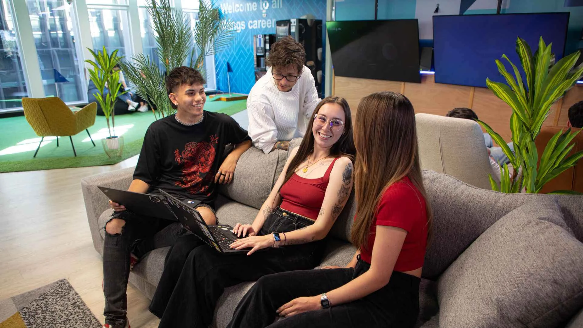 Four people talking in a TP office lounge.