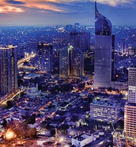 Jakarta cityscape at night with illuminated skyscrapers and busy roads.