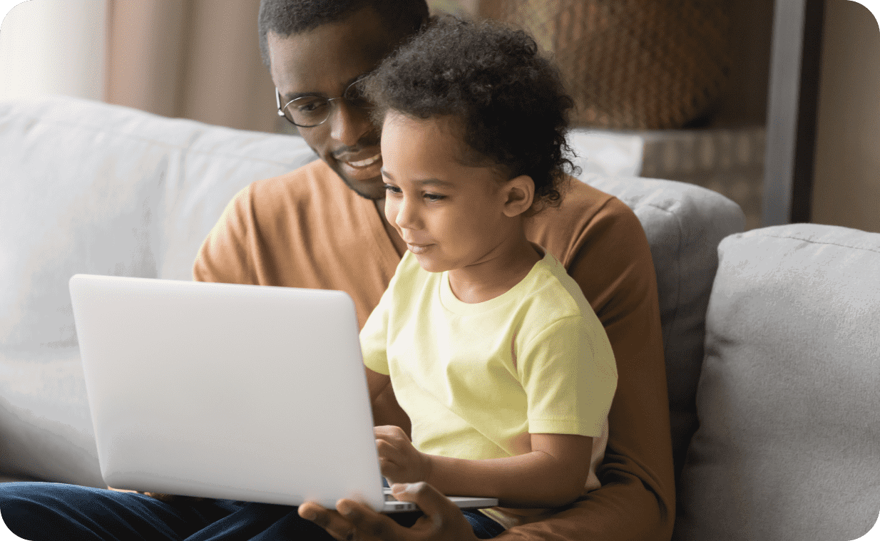 African father browsing laptop with his kid sit on his lap