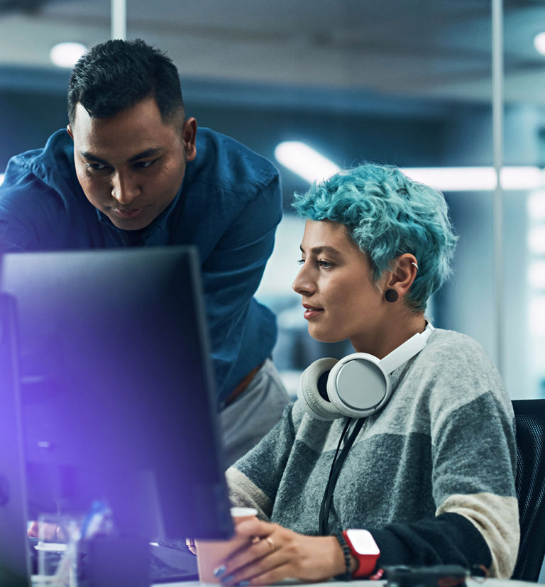 Two colleagues collaborating at computers in a modern technology workspace at TP.