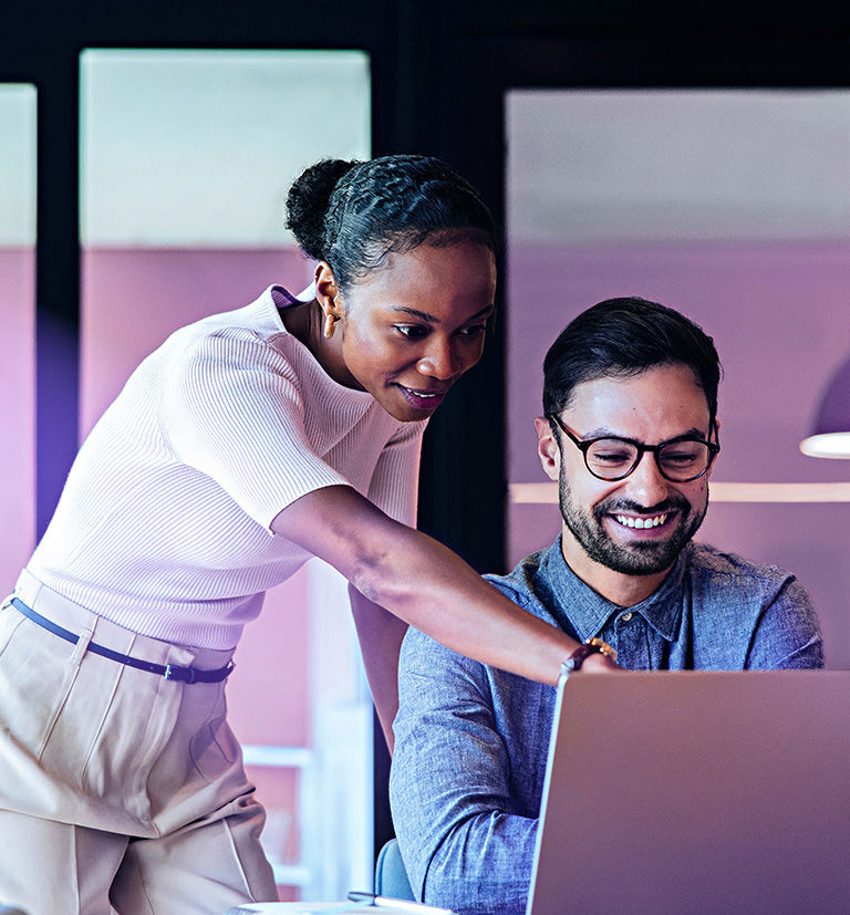 Black woman and white man collaborating on a computer in an office.