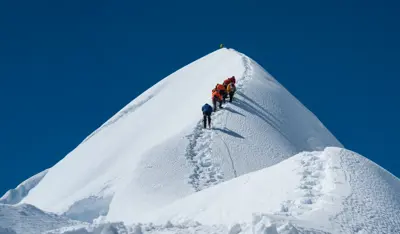 TP team climbing a snow-covered mountain ridge under a clear blue sky.