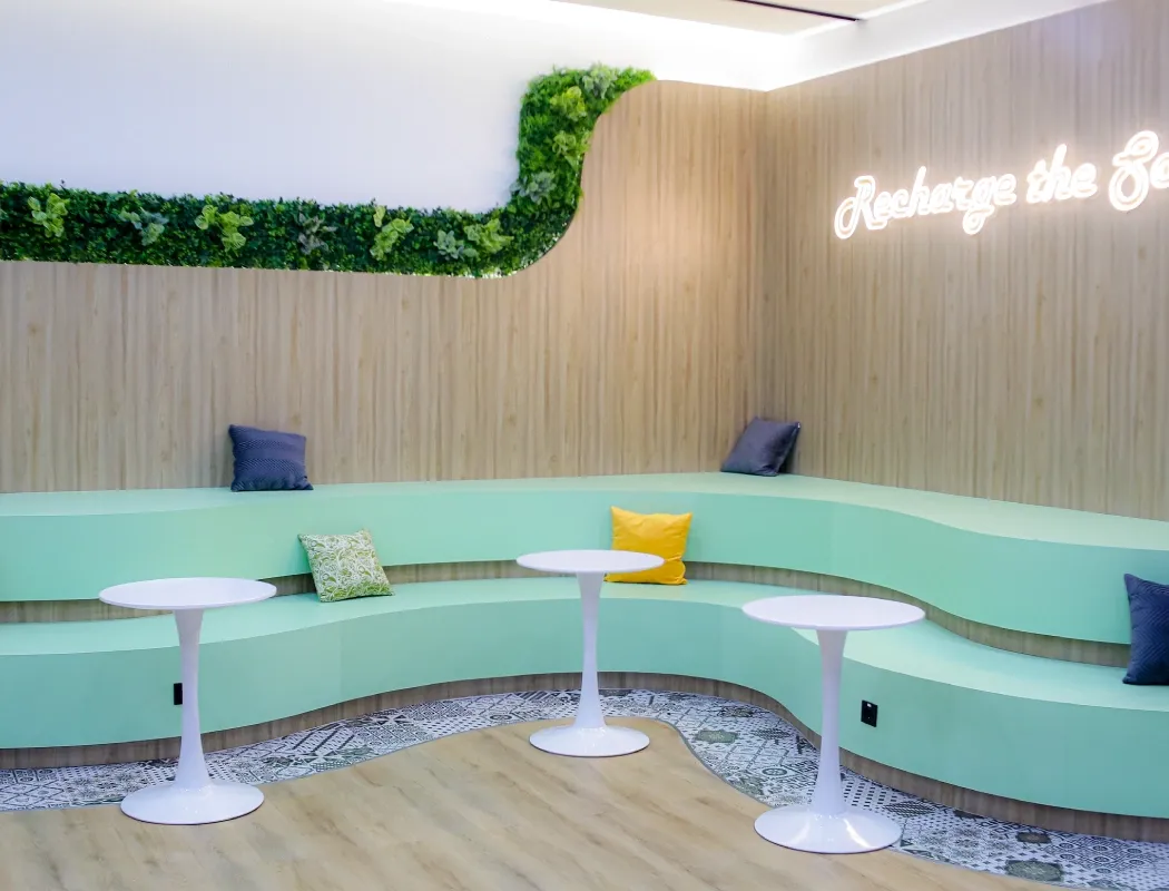 A modern, vibrant office lounge with curved seating and neon decor.
