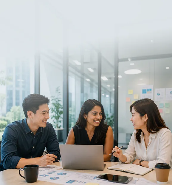 Three colleagues collaborate and discuss ideas in a bright modern office.