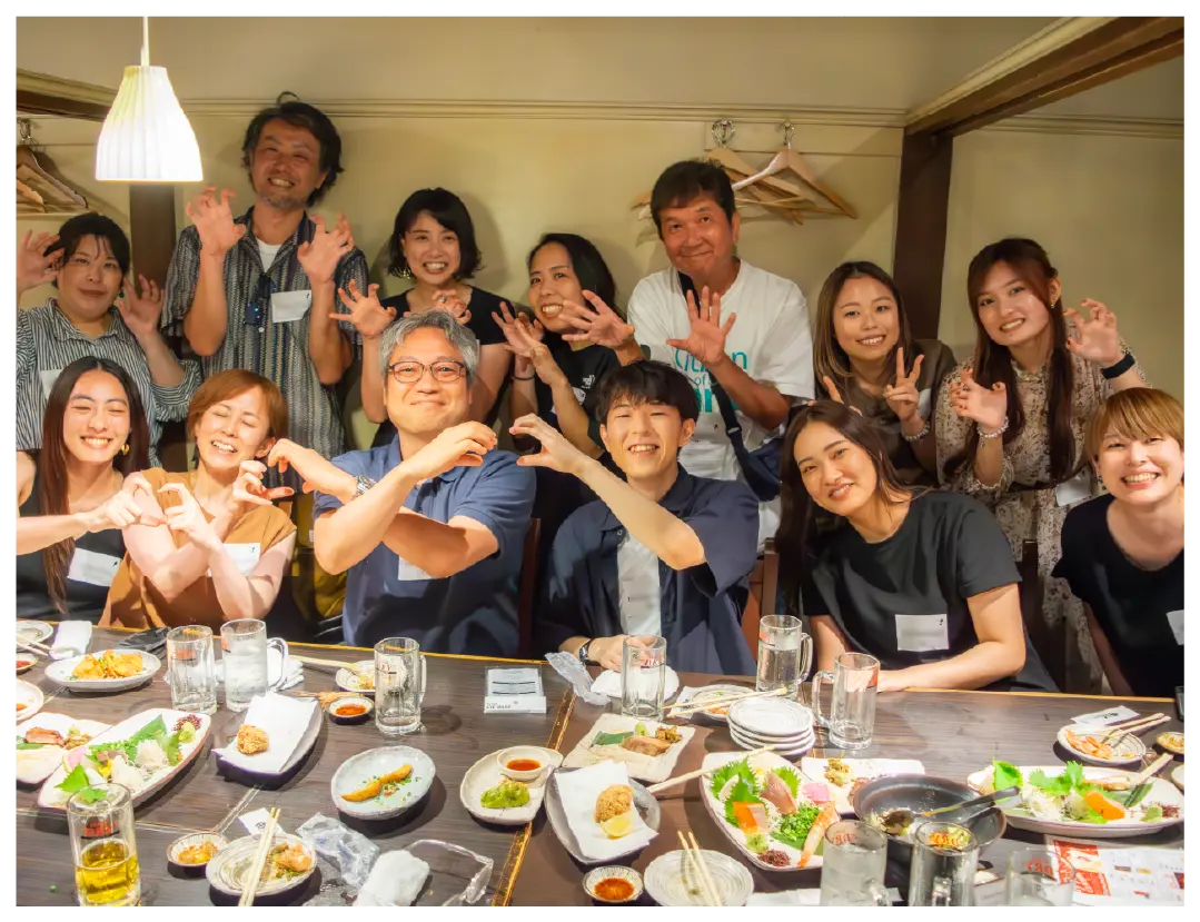 A cheerful group poses playfully at a restaurant dinner gathering.