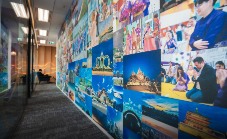 A vibrant photo collage wall decorates a modern office hallway.