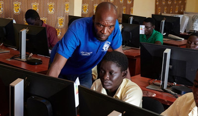Teacher guiding girls using a computer in a technology learning environment.