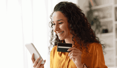 Smiling woman holding a credit card and phone, illustrating a Collections case study.