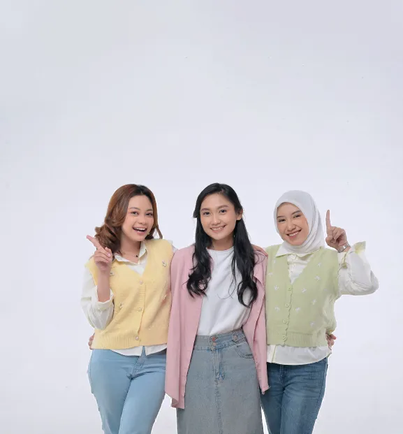 Three diverse young women smile and pose together cheerfully.