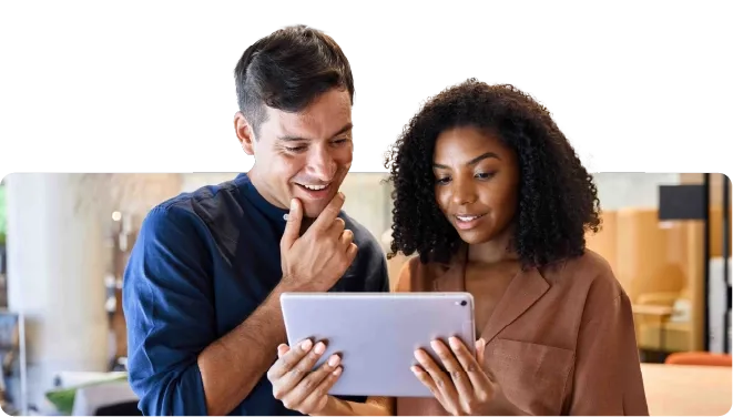 Two colleagues reviewing information together on a tablet in an office setting.