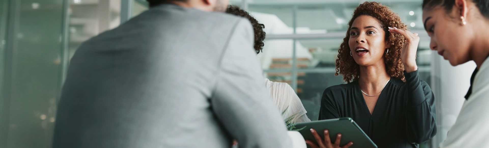 Professional holding a tablet during a team meeting.