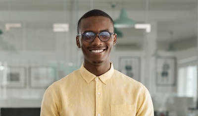 Smiling African man with glasses working in an office, highlighting TP’s innovation award.