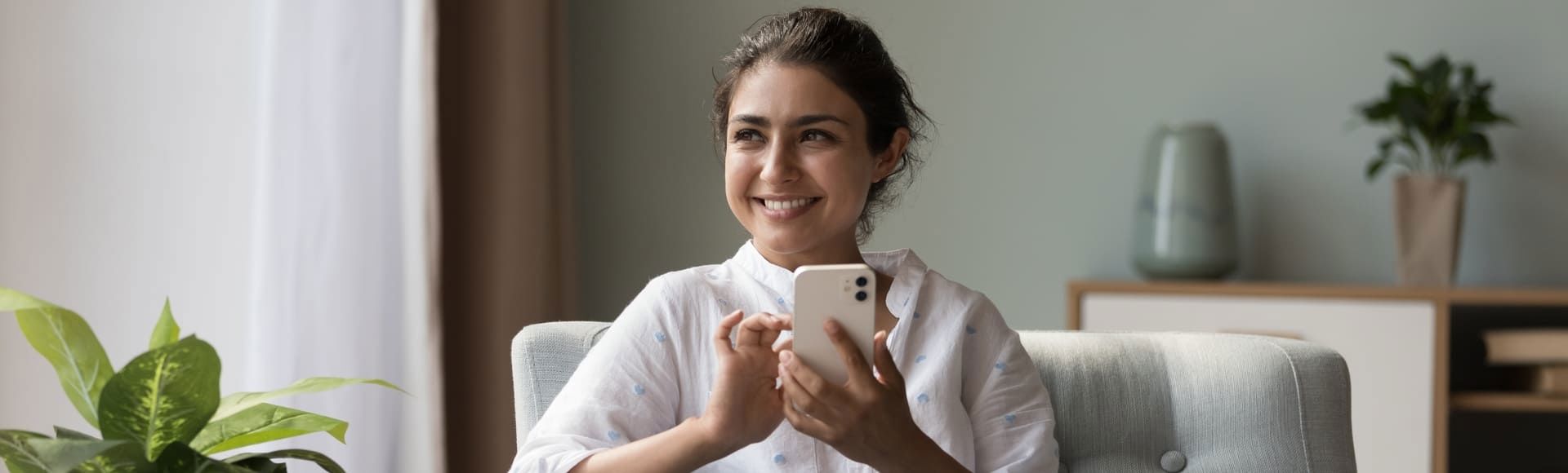 Woman on her sofa using her smartphone, illustrating empathy-driven debt recovery.