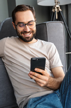 Smiling man sit relaxed while browsing his cellphone.