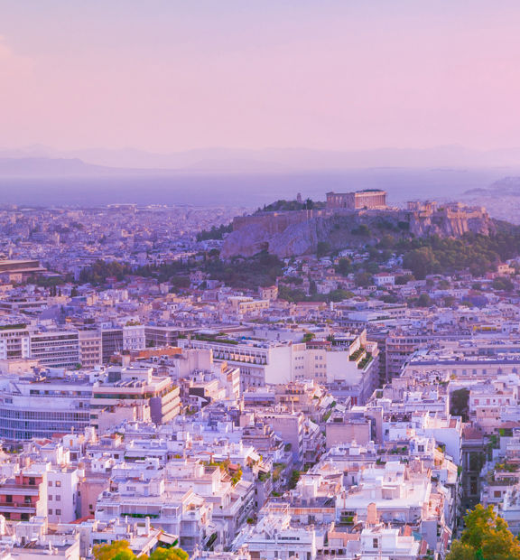 Athens skyline with the Acropolis and surrounding cityscape at sunset.