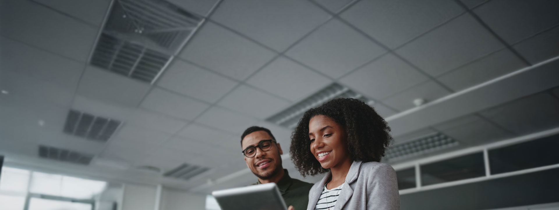 Two young African professionals working on a tablet in a white ceiling office