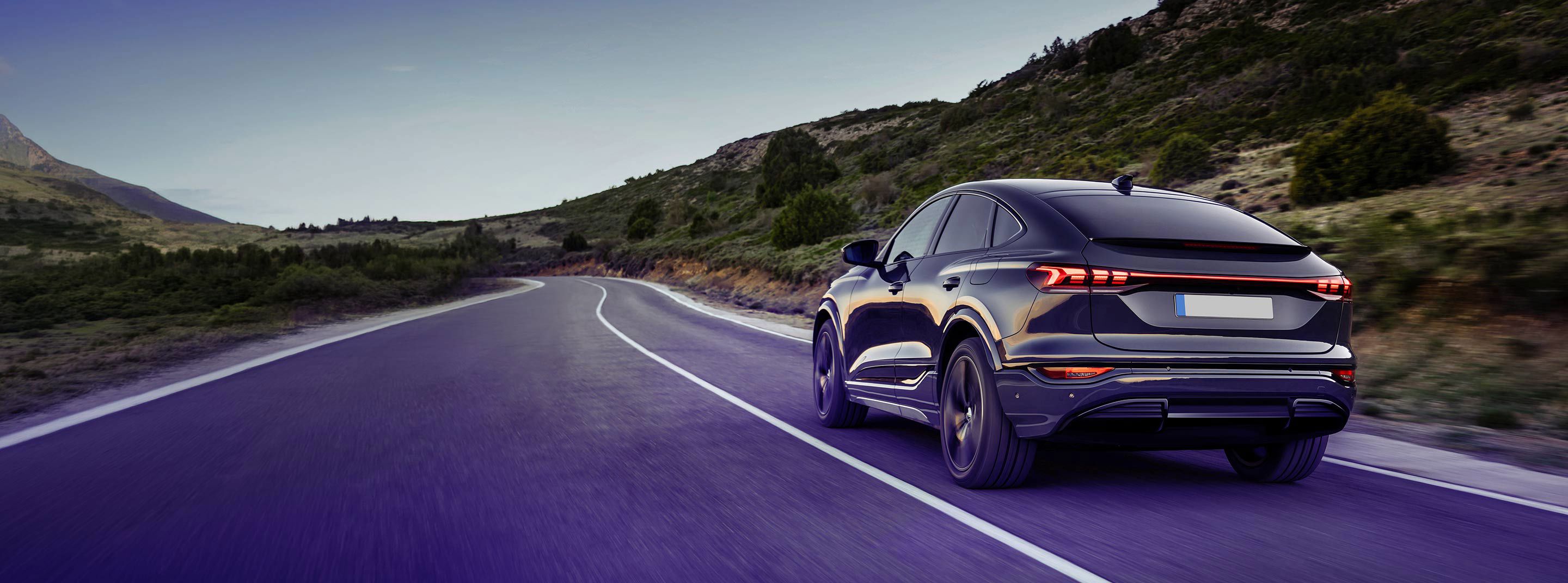Black modern car driving on a road.
