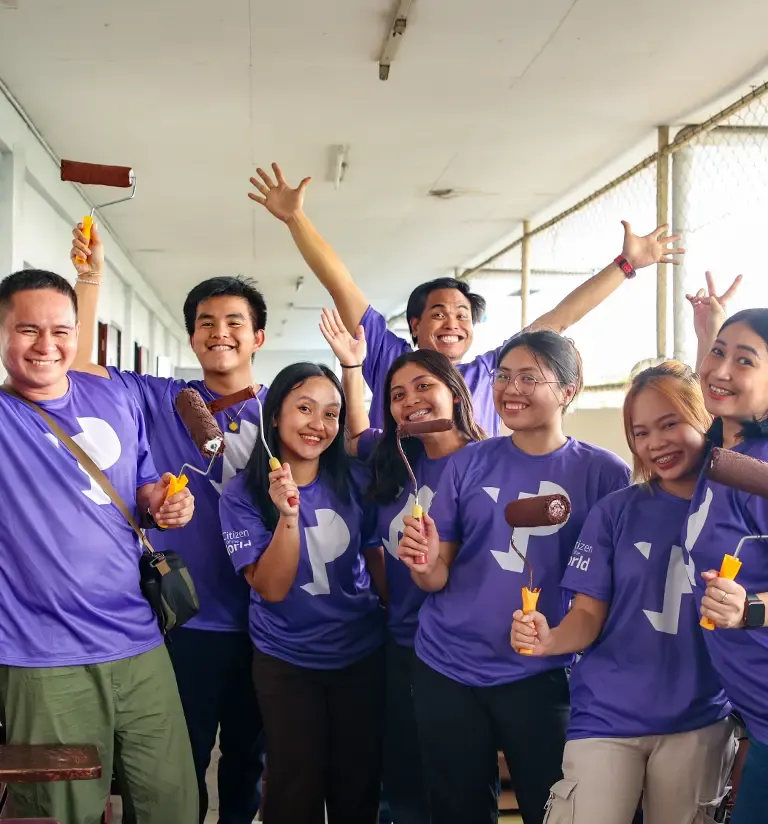 TP employees using brushes and paintbrushes during a community initiative.