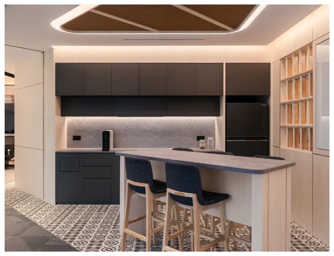 A modern office kitchenette with a central island and stylish seating.